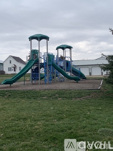 A playground with a green slide and a blue structure.