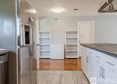 A kitchen with a stainless steel refrigerator and white cabinets.