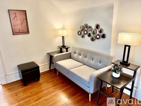 A living room with a grey couch, a small table with a plant, and two lamps.