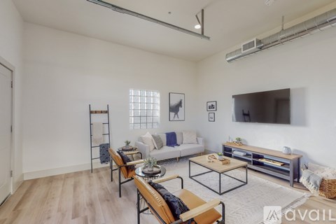A living room with a white couch, a wooden coffee table, and a television mounted on the wall.