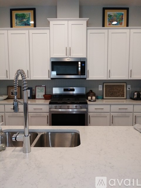 A kitchen with white cabinets and a stainless steel sink.