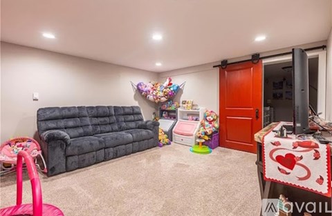 A living room with a grey sofa and a pink stool.