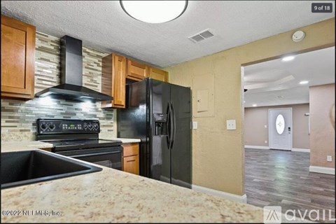 A kitchen with a black stove top oven, black refrigerator, and a black sink.