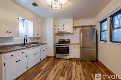A kitchen with white cabinets and wooden floors.
