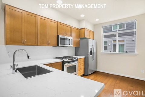 A kitchen with white countertops and wooden cabinets is available for rent.