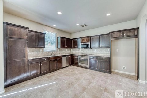A kitchen with dark brown cabinets and a tiled floor.