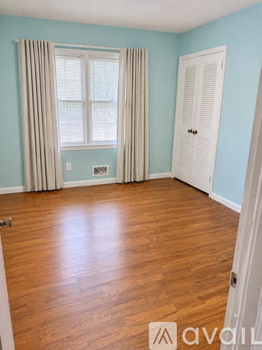 A room with light blue walls and a window with beige curtains.