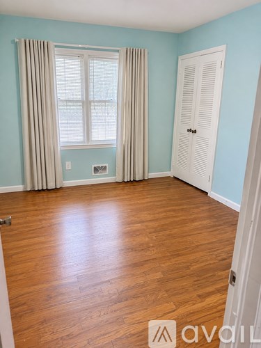 A room with light blue walls and a window with beige curtains.