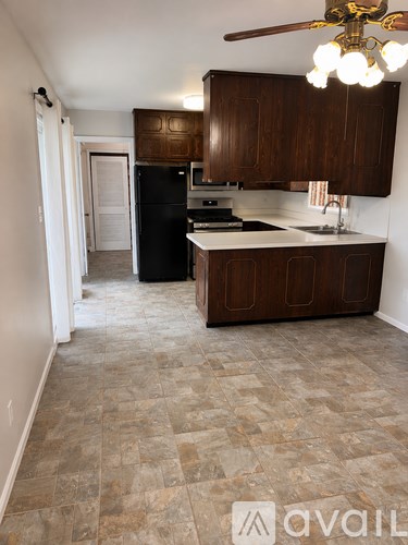 A kitchen with brown cabinets and a black fridge.