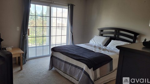 A bedroom with a large bed and a sliding glass door leading to a balcony.