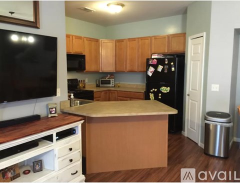A kitchen with a black fridge and wooden cabinets.