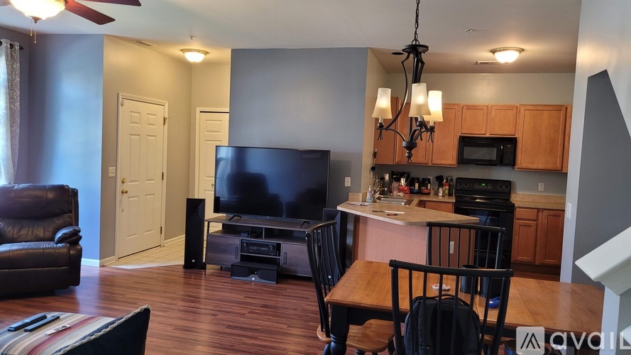 A living room with a television and a kitchen area in the background.