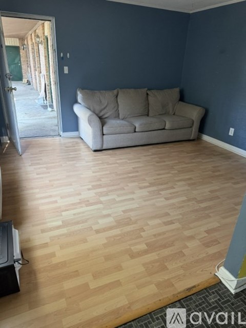 A living room with a grey couch and wooden flooring.