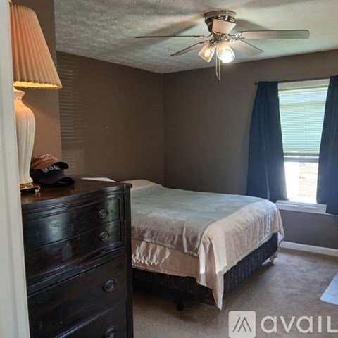 A bedroom with a bed, dresser, and window.