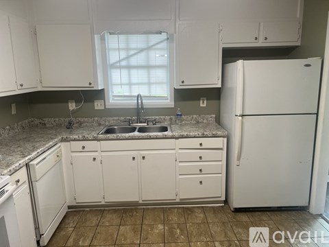 A kitchen with white cabinets and a white refrigerator.