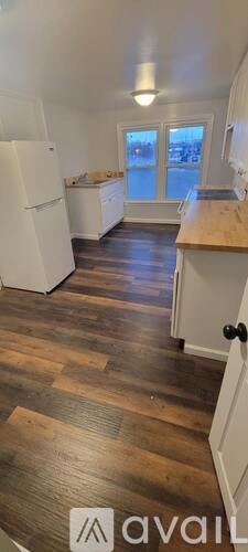 A kitchen with white appliances and wooden floors.