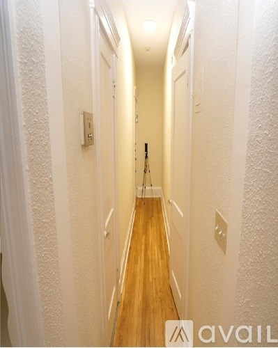 A hallway with wooden floors and white walls.