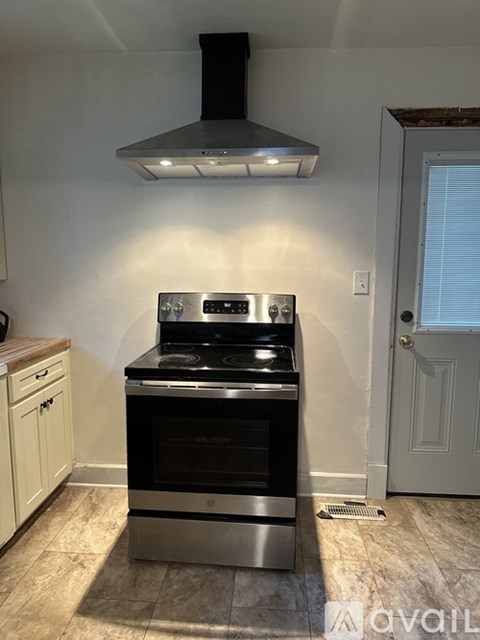 A modern kitchen with a stove top oven and a hood above it.