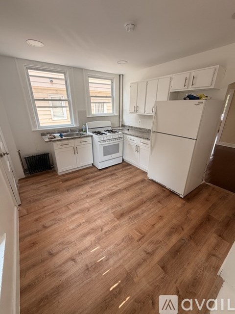 A kitchen with white appliances and wooden floors.