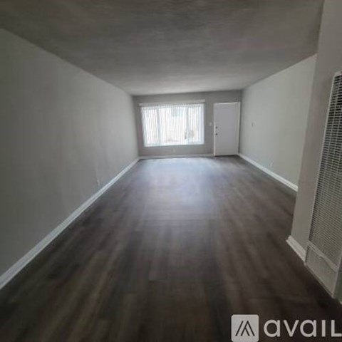 A room with wooden floors and a window with blinds.