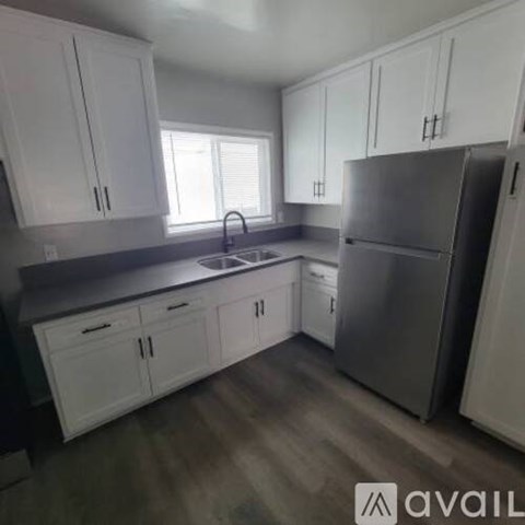 A kitchen with white cabinets and a grey countertop.