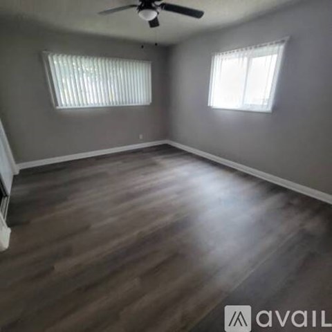 A room with a ceiling fan and two windows.