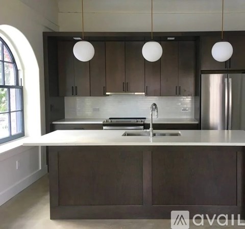 A modern kitchen with dark wood cabinets and a white countertop.