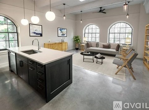 A modern kitchen with a large island and a living area with a couch and chair.