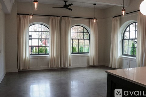 A spacious room with large windows and a ceiling fan.