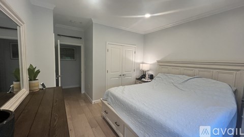 A bedroom with a bed, nightstand, and a mirror on the wall.