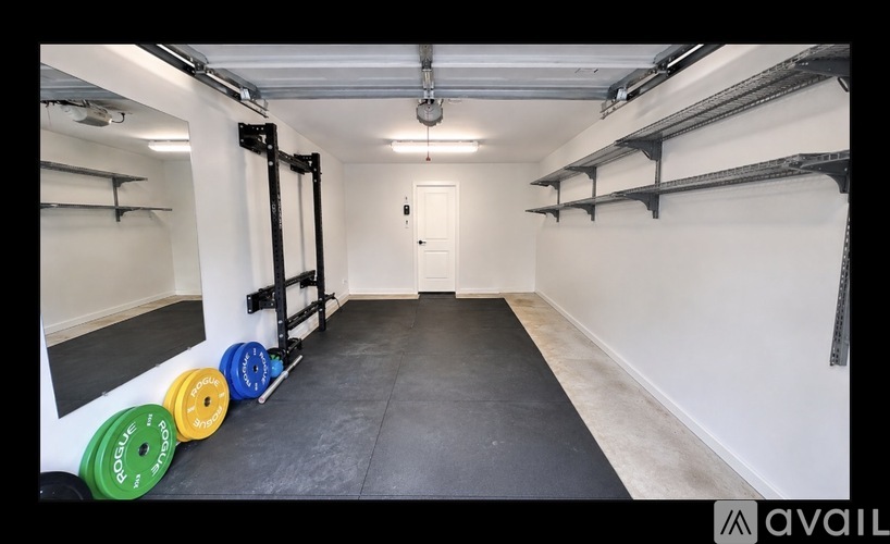 A gym with a black floor, white walls, and a door at the end of the room.