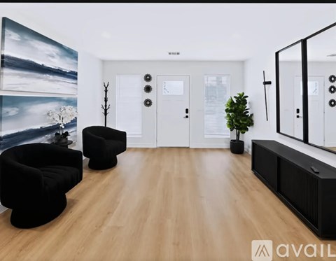 A modern living room with a large painting on the wall and two black chairs.