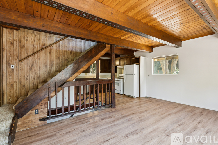 A wooden staircase with a metal railing leads up to a kitchen area.