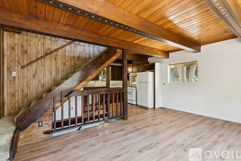 A wooden staircase with a metal railing leads up to a kitchen area.