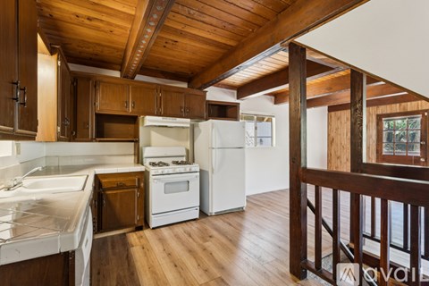 A kitchen with wooden cabinets and a white stove top oven.