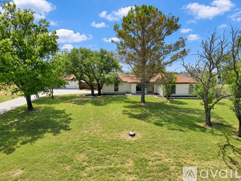 A house is surrounded by trees and grass in the foreground.