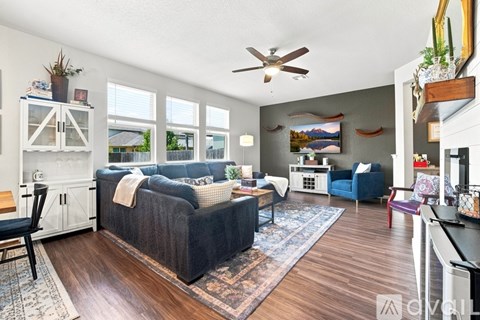 A living room with a black couch and a ceiling fan.