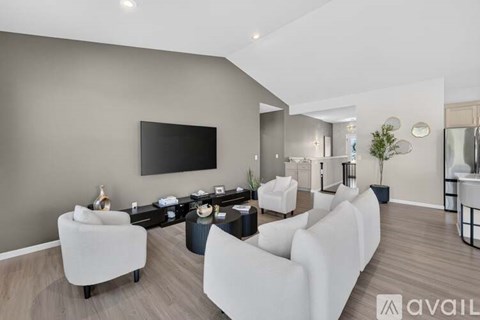 A modern living room with white furniture and a flat screen TV mounted on the wall.
