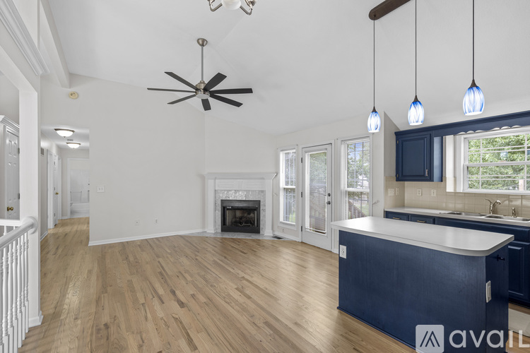 A spacious living room with a fireplace and a ceiling fan.