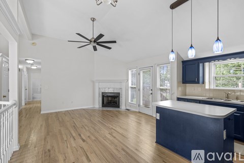 A spacious living room with a fireplace and a ceiling fan.