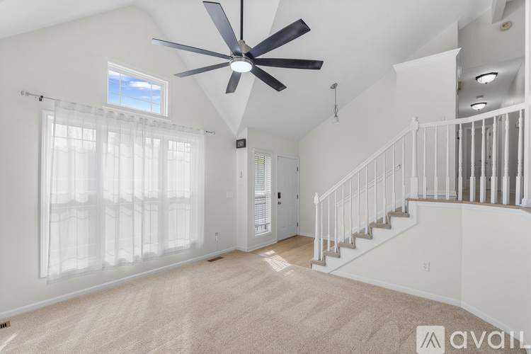 A spacious room with a fan and a staircase.