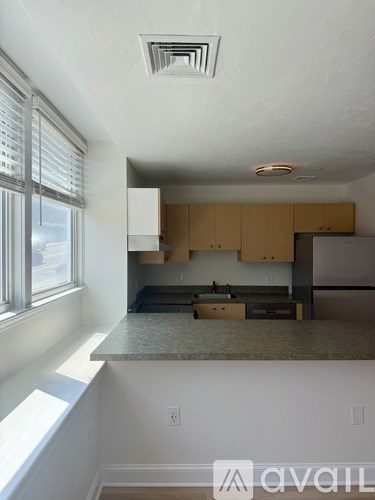 A kitchen with wooden cabinets and a window with blinds.