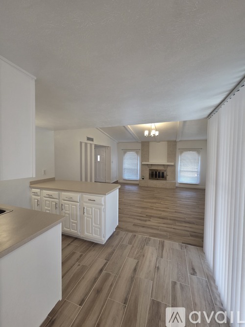 A spacious kitchen with white cabinets and a wooden floor.
