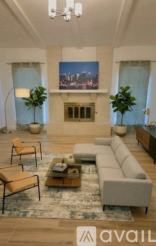 A living room with a large couch, a coffee table, and a painting of a city skyline on the wall.
