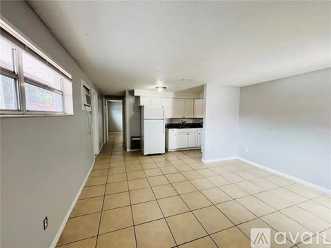 A kitchen area with white appliances and tiled flooring.