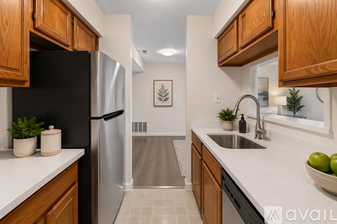 A kitchen with wooden cabinets and a black fridge.
