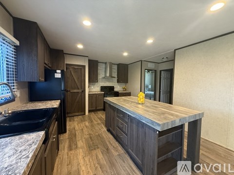 A kitchen with dark wood cabinets and a granite countertop.