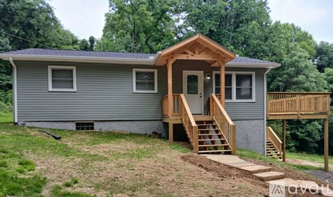 A small house with a wooden porch and stairs leading to the door.
