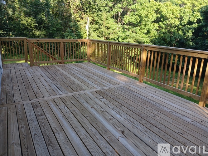 A wooden deck with a railing and trees in the background.