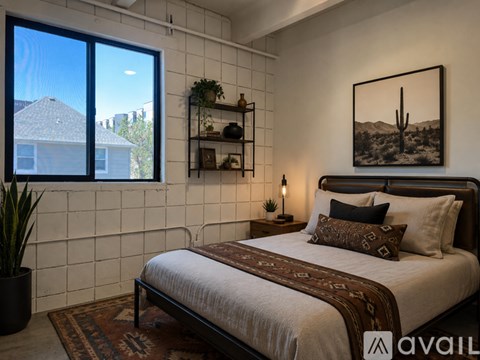 A bedroom with a large bed and a cactus plant on the windowsill.